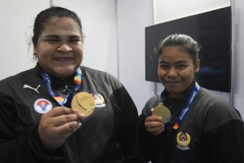 ifter Indonesia Melinda Gusti (kanan) dan Nurul Akmal menunjukkan medali emas yang mereka peroleh pada nomor angkat besi putri 75 dan +75 kg 18th Asian Games Invitation Tournament di JiExpo, Jakarta, Senin (12/2). 