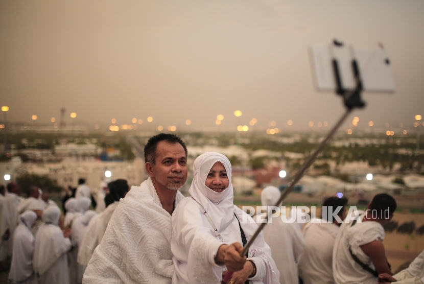 Umroh saat Ramadhan tidak bisa disejajarkan dengan kewajiban haji. Ilustrasi jamaah melakukan foto selfie saat memakai pakaian umrah.