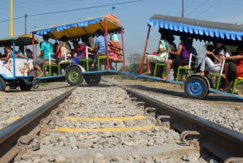 Ilustrasi kereta kelinci melintas melewati rel kereta api. 