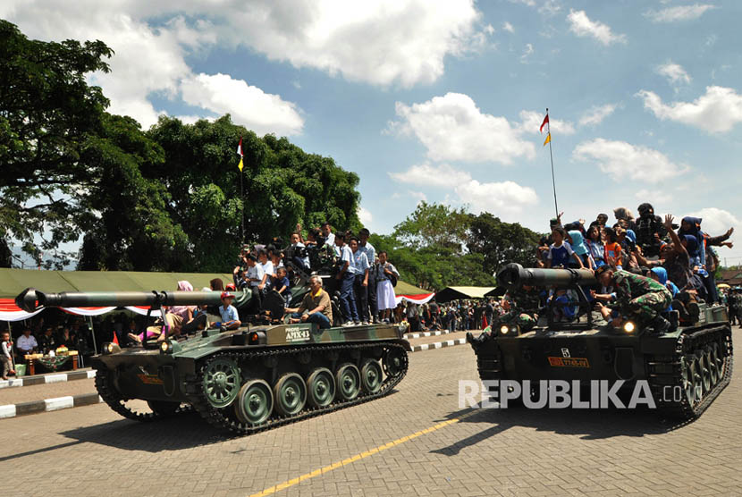 Ilustrasi Warga menumpang kendaraan tempur saat defile alutsista TNI.
