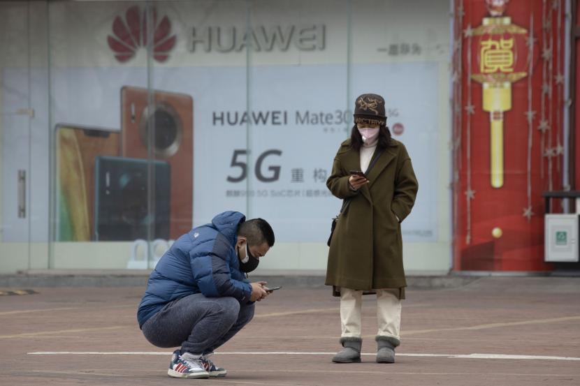 ilustrasi:5G - Dalam foto Minggu, 8 Maret 2020 ini, warga yang memakai topeng melihat smartphone mereka di dekat iklan smartphone 5G dari raksasa teknologi China Huawei di Beijing.