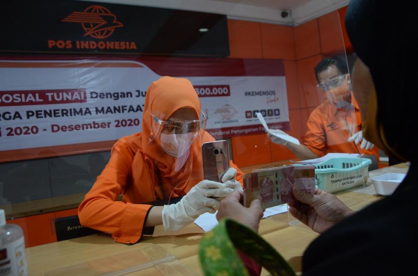 Petugas memotret identitas penerima bantuan sebagai tanda bukti saat Penyaluran Bantuan Sosial Tunai (BST), di Kantor Pos, Jalan PHH Mustofa, Kota Bandung, Rabu (5/8). BST dengan jumlah Rp 300.000 itu diberikan kepada Keluarga Penerima Manfaat (KPM).