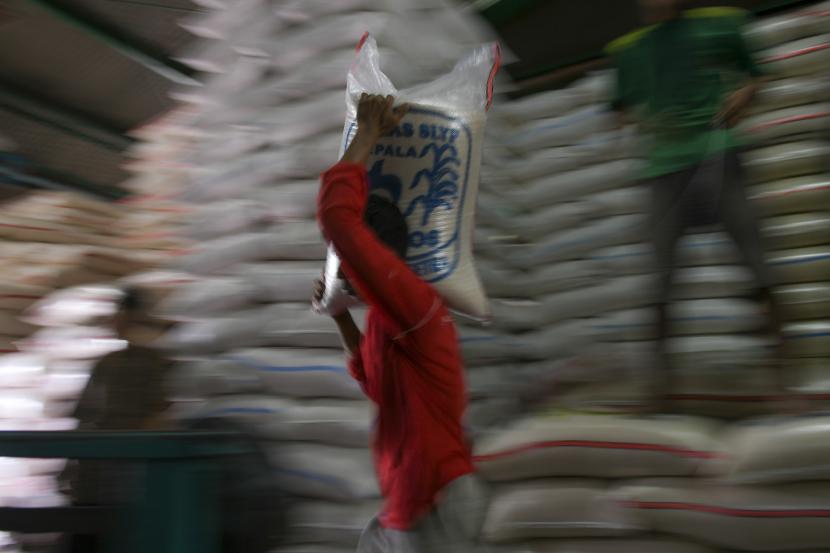 Pekerja memanggul karung berisi beras.