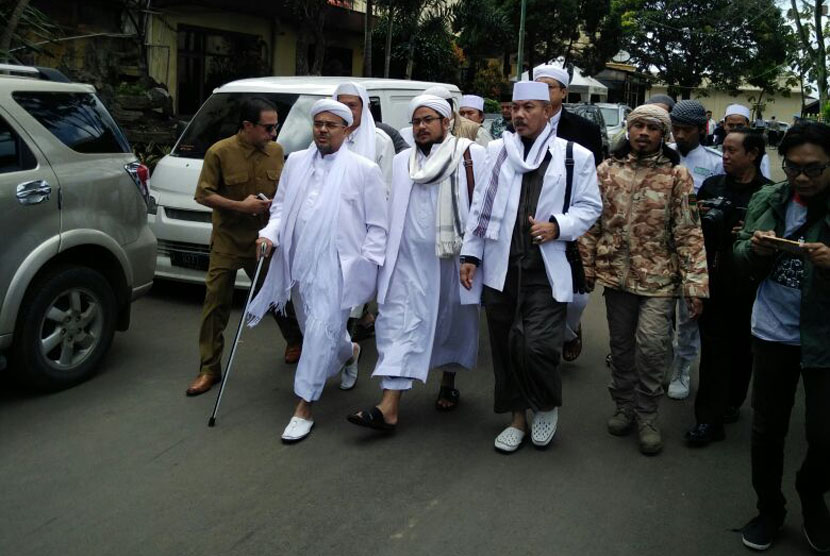 Imam Besar FPI Habib Rizieq Shihab (tengah) berjalan memasuki ruangan di Polda Jabar, Bandung, Senin (13/2).