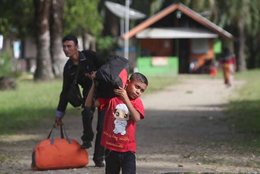 Imigran Rohingya mengangkut barang-barangnya saat persiapan pemindahan.