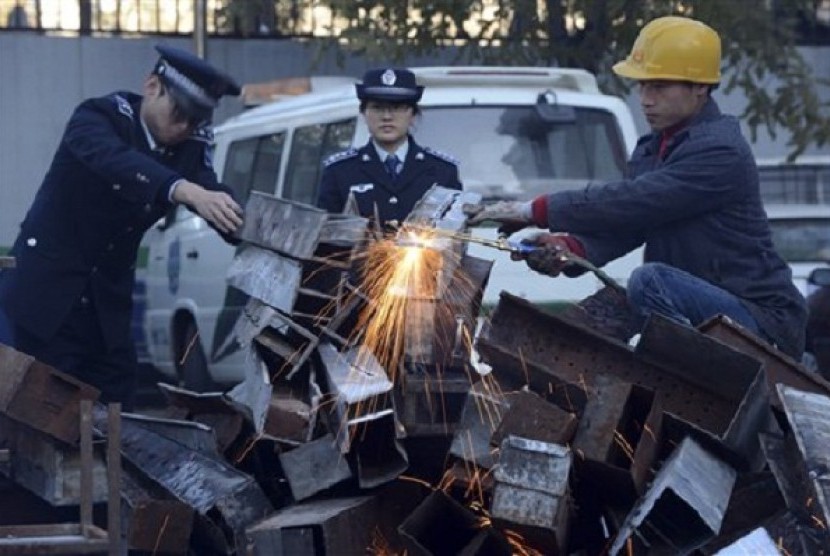 In Nov. 26 photo, municipal officers observe as a worker break down confiscated open-air barbecues confiscated in the past three months in Xicheng district in Beijing, China. (file photo)