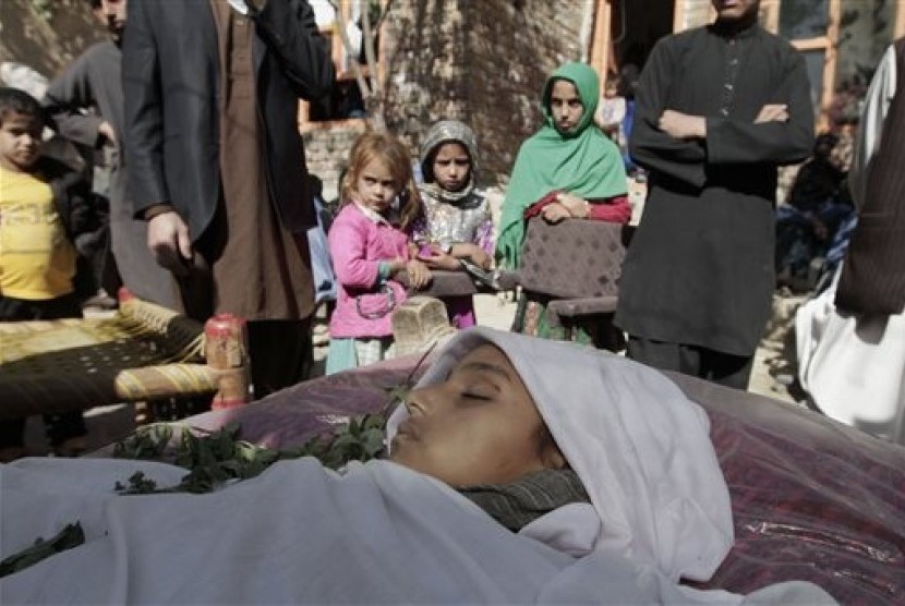 In this file photo taken Sunday, Oct. 27, 2013, relatives surround the body of a ten-year-old Afghan girl who was killed by a roadside bomb explosion on the outskirts of Kabul, Afghanistan. 