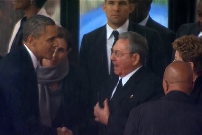 In this image from TV, US President Barack Obama shakes hands with Cuban President Raul Castro at the FNB Stadium in Soweto, South Africa, in the rain for a memorial service for former South African President Nelson Mandela, Tuesday Dec. 10, 2013. 