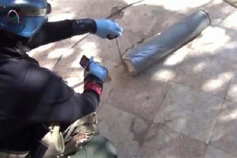 In this image taken from amateur video posted online, appearing to show a presumed UN staff member measuring and photographing a canister in the suburb of Moadamiyeh in Damascus, Syria, Monday Aug. 26, 2013.