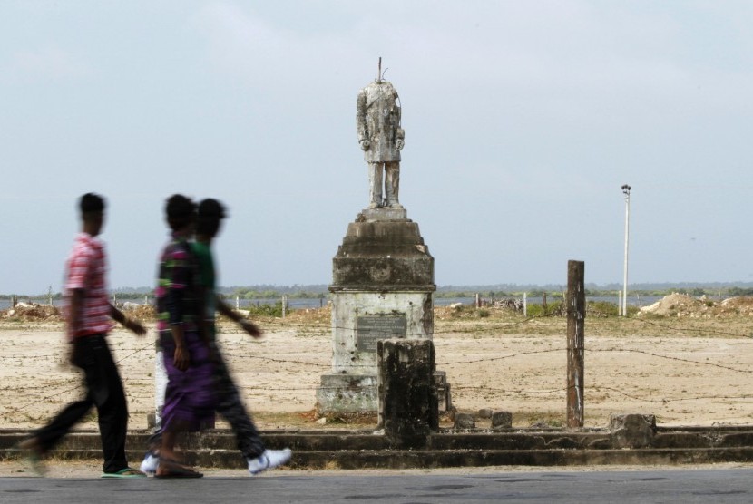 In this July 25, 2011 photo, Sri Lankan ethnic Tamils walk past a beheaded statute of a prominent Tamil social leader in Jaffna, Sri Lanka. The road blocks have been dismantled, the sandbags removed, and Sri Lanka is again a palm-fringed tourist paradise, 