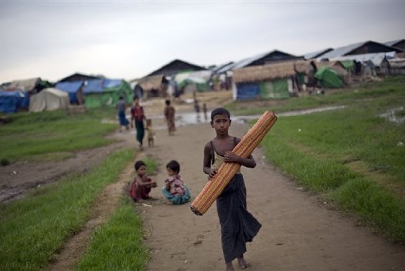 In this June 24, 2014 photo, an ethnic Rohingya boy, who was displaced following 2012 sectarian violence, walks with a mat at Dar Paing camp for refugees in north of Sittwe, Rakhine State, Myanmar.