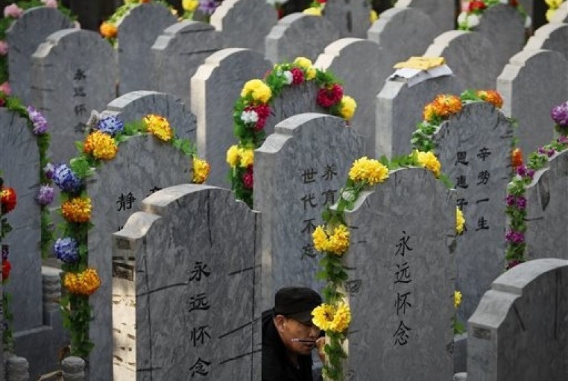 In this Tuesday, April 5, 2011 file photo, a Chinese man repaints the characters on a tomb of his deceased relative at a cemetery on the Qingming Festival in Beijing, China. 