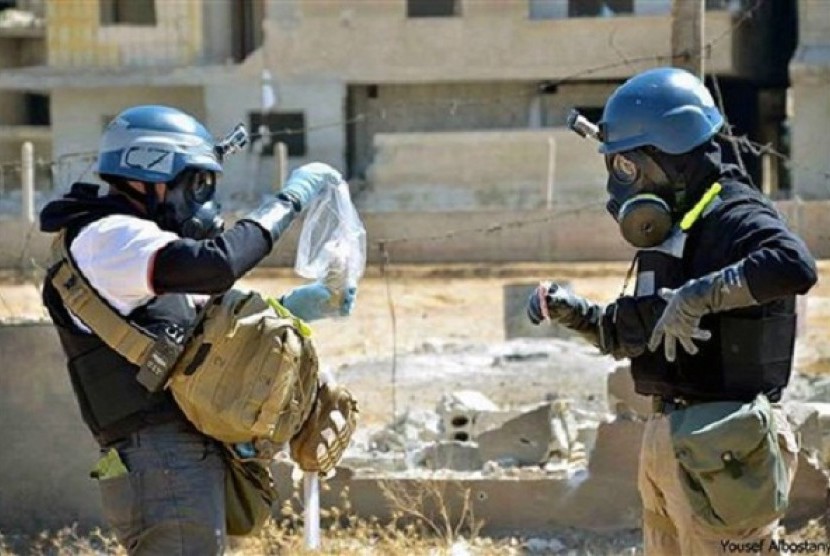 In this Wednesday, Aug. 28, 2013, file photo, a citizen journalism image provided by the United Media Office of Arbeen, shows members of the United Nations investigation team take samples from sand near a part of a missile that is likely to be a chemical r