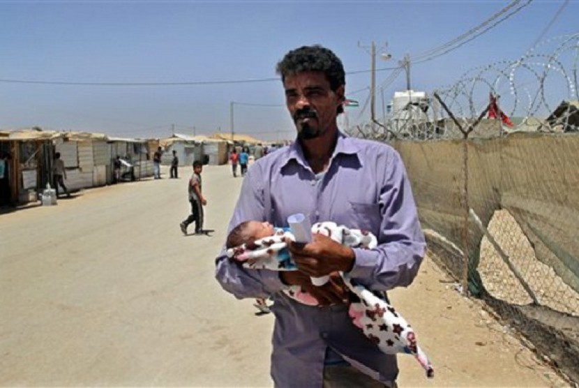 In this Wednesday, July 24, 2013 photo, Syrian refugee Ali Shteiwi holds his newborn daughter, Taymaa, at the Zaatari refugee camp in Mafraq, Jordan, near the border with Syria. 