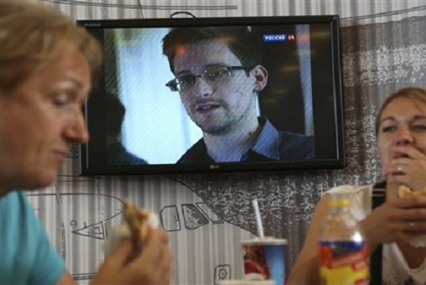 In this Wednesday, June 26, 2013 file photo transit passengers eat at a cafe with   a TV screen with a news program showing a report on Edward Snowden, in the   background, at Sheremetyevo airport in Moscow, Russia.