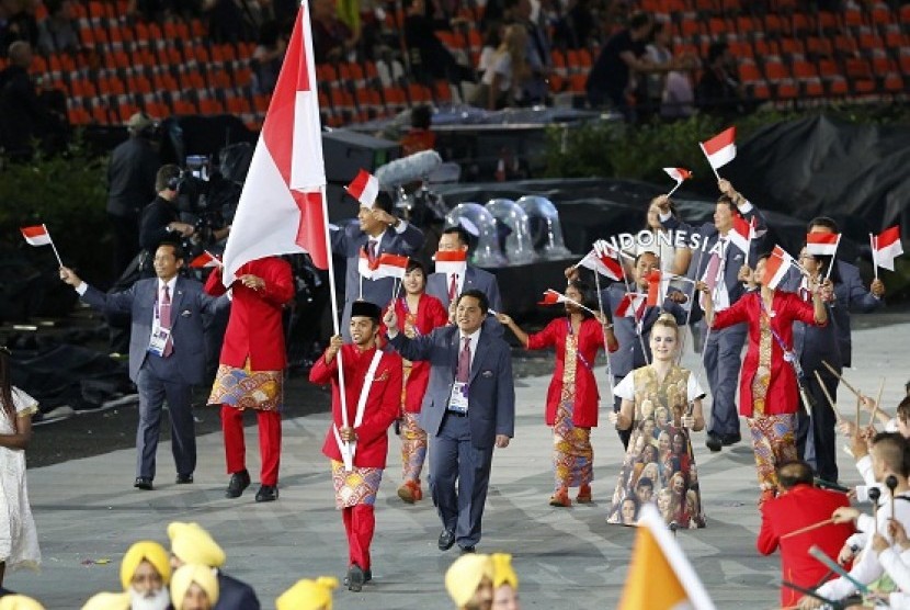 Indonesia's flag bearer Gede Sudartawa holds the national flag as he leads the contingent in the athletes parade during the opening ceremony of the London 2012 Olympic Games at the Olympic Stadium July 27, 2012. While Erick Thohir steps behind Sudartawa.  