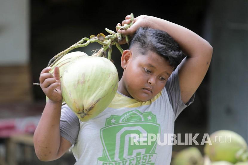 Seorang warga membawa kelapa muda. Air kelapa muda memiliki kandungan elektrolit yang tinggi.