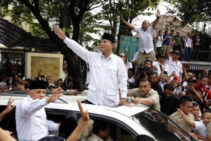 Indonesian presidential candidate Prabowo Subianto (center) and his vice presidential running mate Hatta Rajasa wave to supporters after registering at the Election Commission, May 20, 2014.