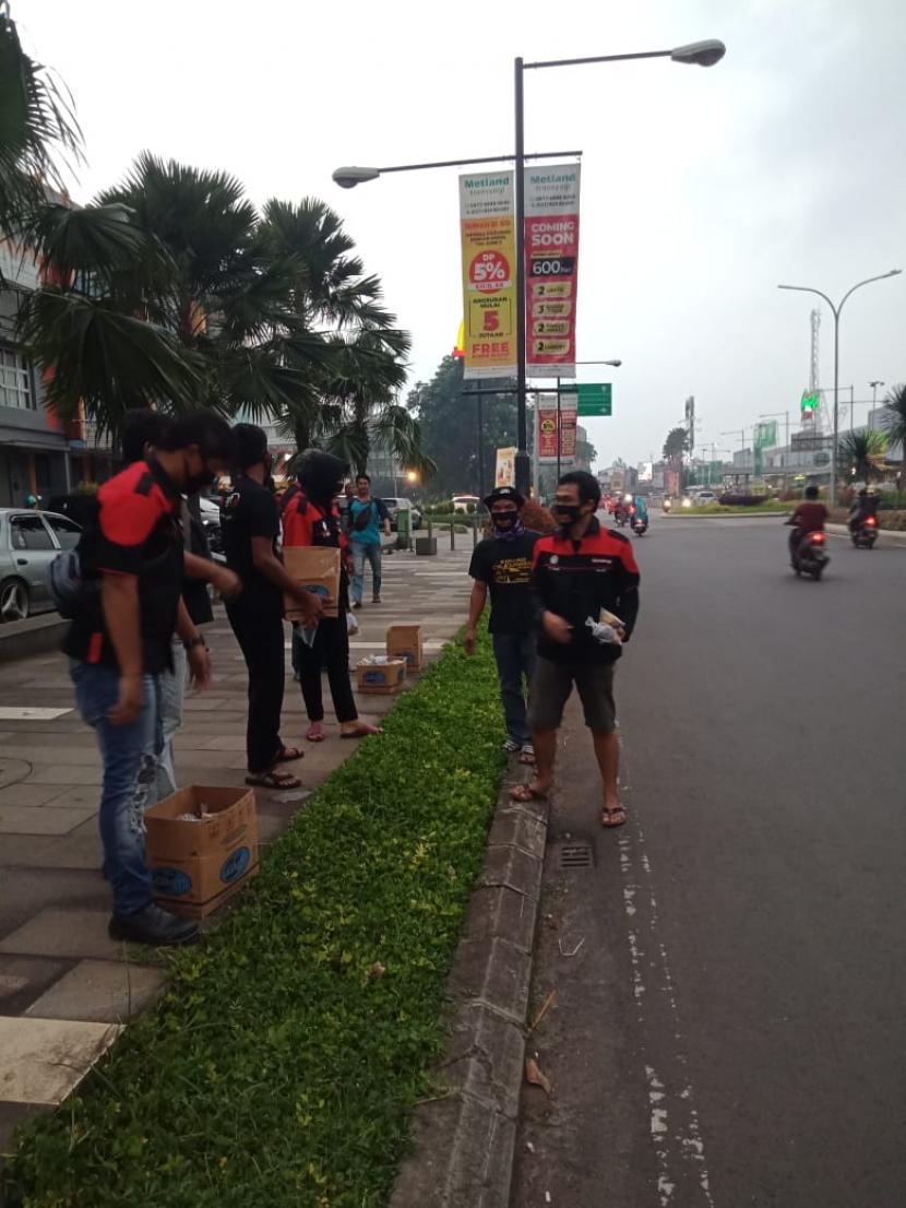 Internasional Network for Humanitarian (INH) menggandeng komunitas mobil Timorer Becika Squad Cileungsi, membagikan ratusan masker dan takjil kepada para pengendara sepeda motor dan mobil yang melintas di Jalan Raya Ciulengsi-Jonggol, Kabupaten Bogor, Ahad (26/4).