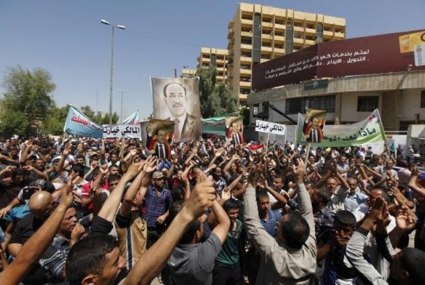 Iraqis carry portraits of incumbent Iraqi Prime Minister Nuri al-Maliki as they gather in support of him in Baghdad August 13, 2014. 