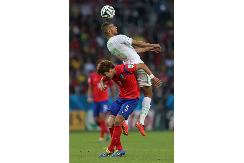 Islam Slimani (atas) dari Aljazair beraksi dengan Kim Younggwon dari Korea Selatan selama Piala Dunia FIFA 2014 grup H pertandingan babak penyisihan antara Korea Selatan dan Aljazair di Estadio Beira-Rio di Porto Alegre, Brasil,  Minggu (22/6).  (EPA/Moham