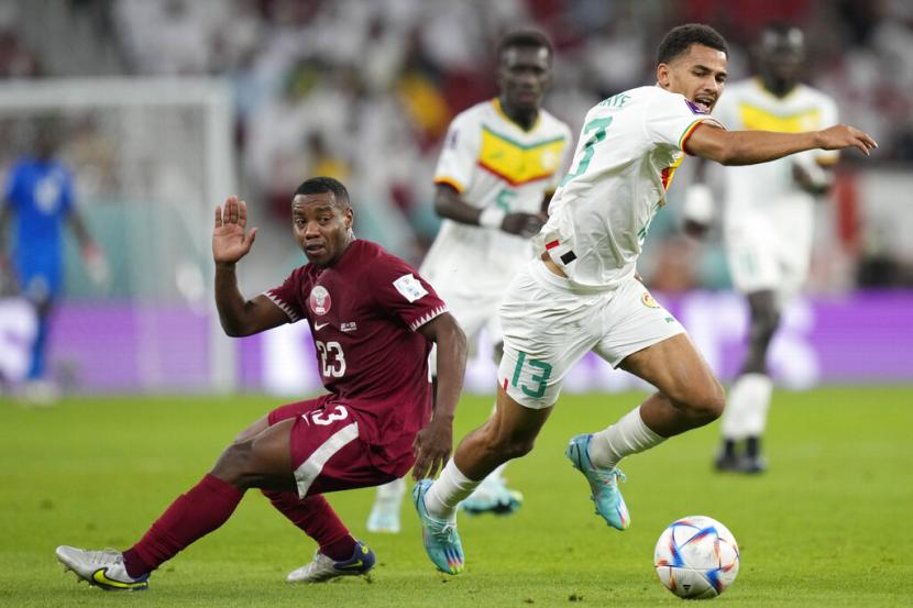 Ismail Jakobs dari Senegal (kanan) menggiring bola melewati Assim Madibo dari Qatar selama pertandingan sepak bola grup A Piala Dunia antara Qatar dan Senegal, di Stadion Al Thumama di Doha, Qatar, Jumat, 25 November 2022.
