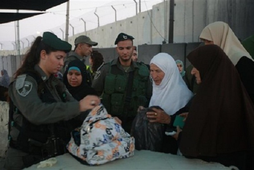 Israeli border police officers check the bag of Palestinian worshippers as they wait to cross through an Israeli checkpoint on their way to pray at the Al-Aqsa Mosque in Jerusalem, on Friday, July 12, 2013. Israel occcupies the land for more than 60 years.