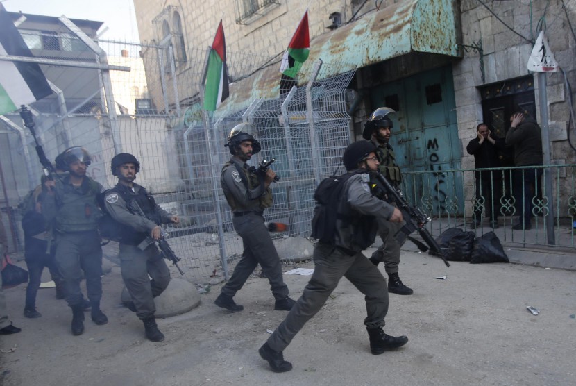 Israeli border policemen run after Palestinians during a protest against the visit of Israeli President Reuven Rivlin to the occupied West Bank city of Hebron, in Hebron February 2, 2015. 