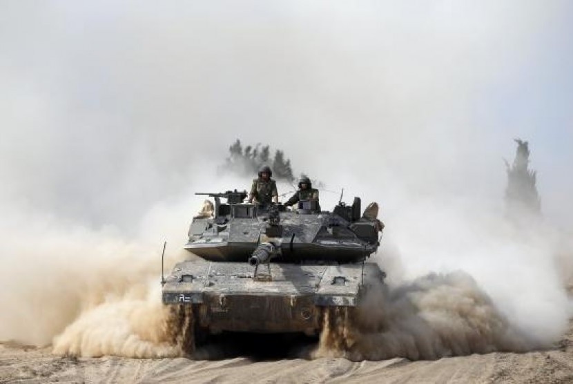 Israeli soldiers ride atop a tank outside the southern Gaza Strip July 7, 2014.