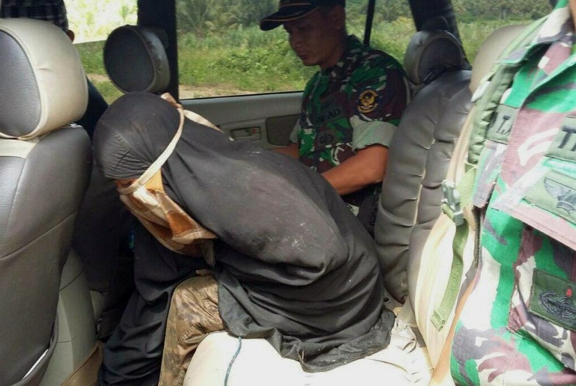   Isteri Santoso, Jumiatun alias Umi Delima (kiri) diamankan anggota Satgas Operasi Tinombala setelah menyerahkan diri di Poso, Sulawesi Tengah, Sabtu (23/7).