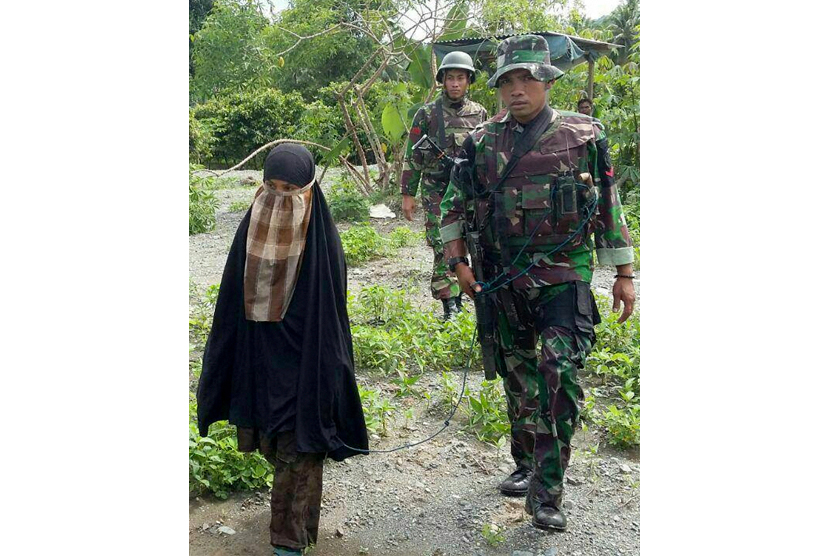 Isteri Santoso, Jumiatun alias Umi Delima (tengah) diamankan anggota Satgas Operasi Tinombala setelah menyerahkan diri di Poso, Sulawesi Tengah, Sabtu (23/7). 