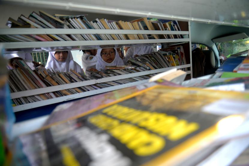 iswa mengambil buku bacaan dari mobil Perpustakaan Keliling.