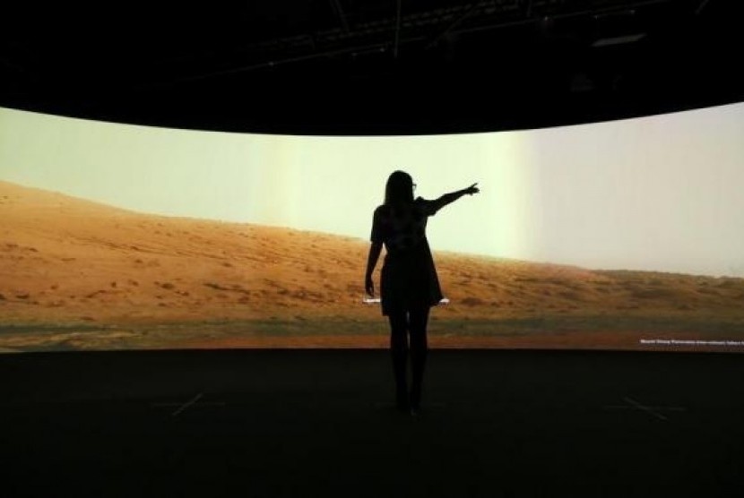 Jacqueline Storey, a press officer at the National Maritime Museum, poses for a photograph in front of images of Mars generated by NASA's Curiosity Rover at their new Visions of the Universe exhibition, in Greenwich, London June 5, 2013.