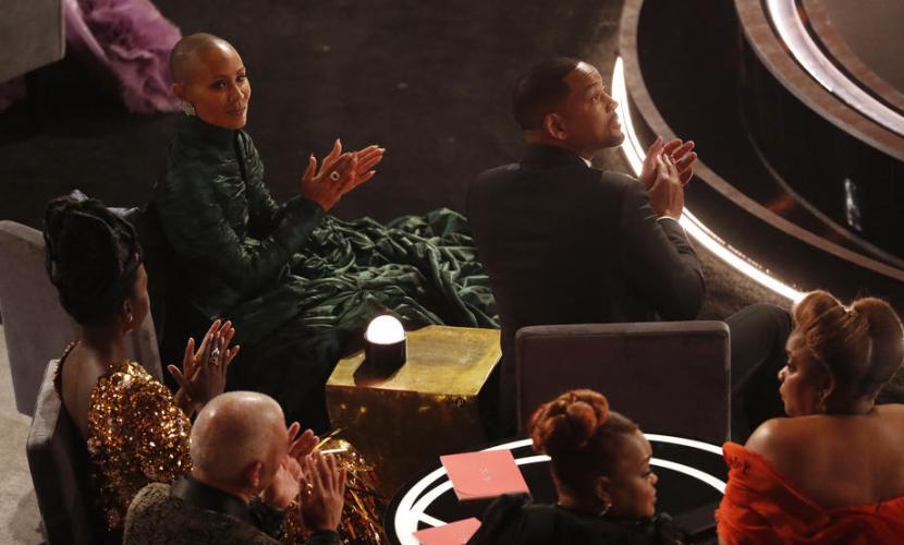 Jada Pinkett Smith (kiri) dan suaminya Will Smith tampak menyimak saat presenter-komedian Chris Rock berada di panggung Oscar, Ahad (27/3/2022).
