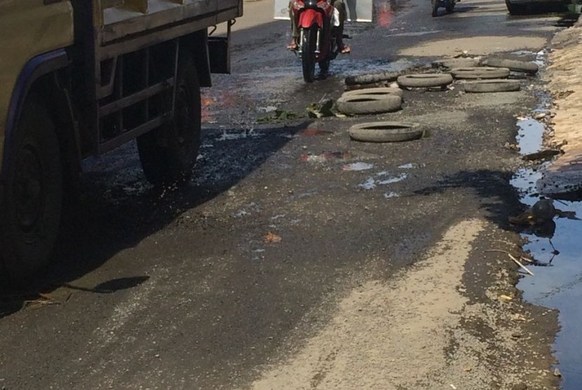 Jalan Raya Bintara Raya Bekasi Barat yang rusak parah ditambal secara darurat oleh warga dengan ban bekas
