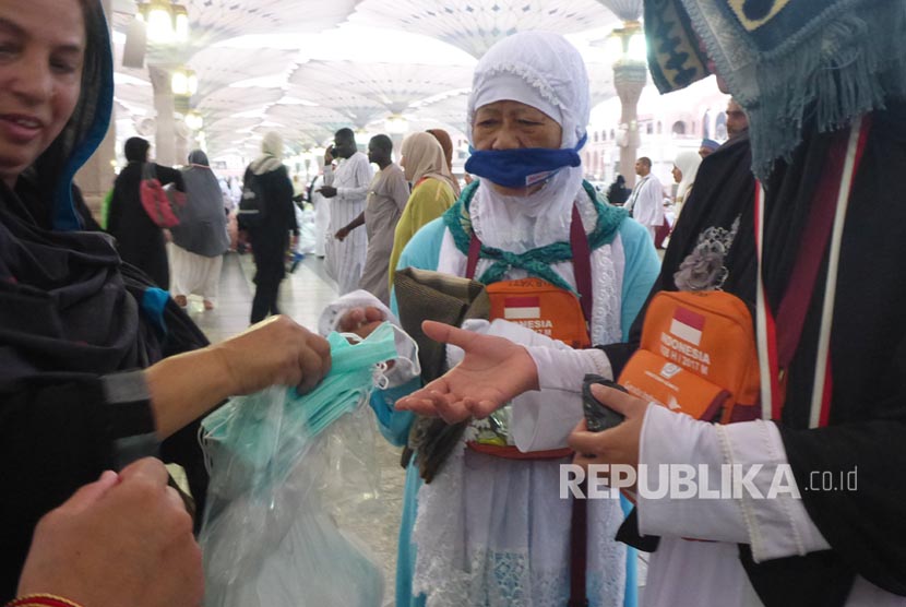 Jamaah asal India membagikan masker gratis kepada jamaah haji di Masjid Nabawi jelang maghrib, Selasa (15/8). 