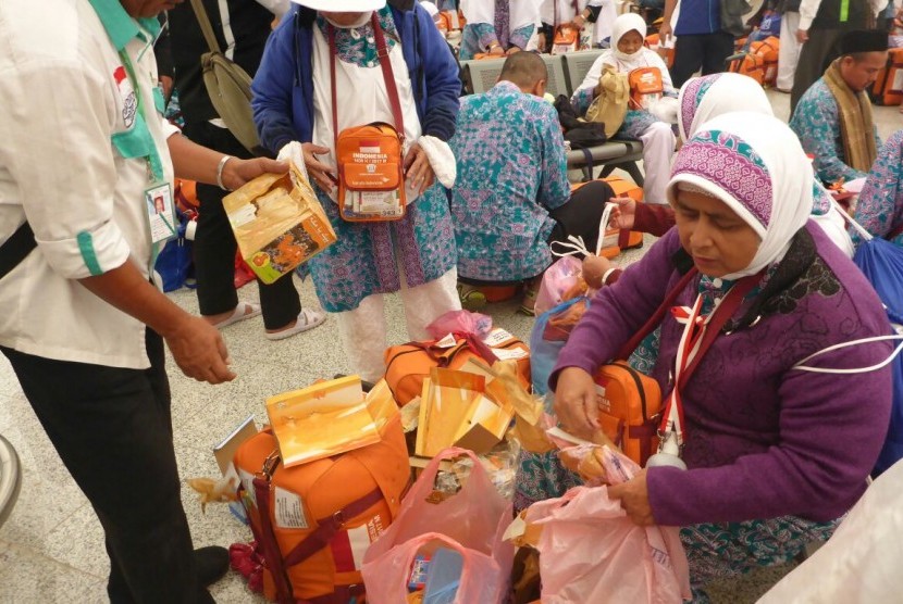 Jamaah haji embarkasi SOC 48 asal Tegal, Saronah Sakib Wajad (59 tahun) dengan dibantu petugas haji membuang kemasan mainan hasil buruannya di Makkah, di Paviliun Haji Bandara Amir Muhammad Bin Abdul Aziz, Madinah, Kamis (21/9). 