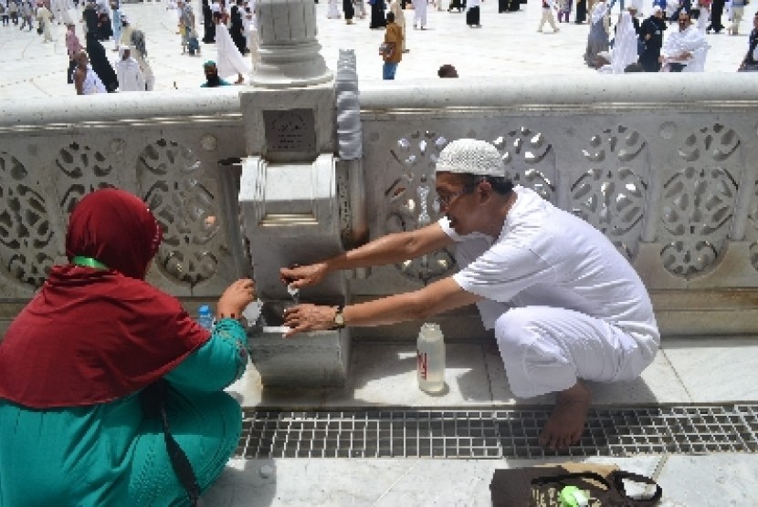 Jamaah haji tengah mengambil air zamzam.