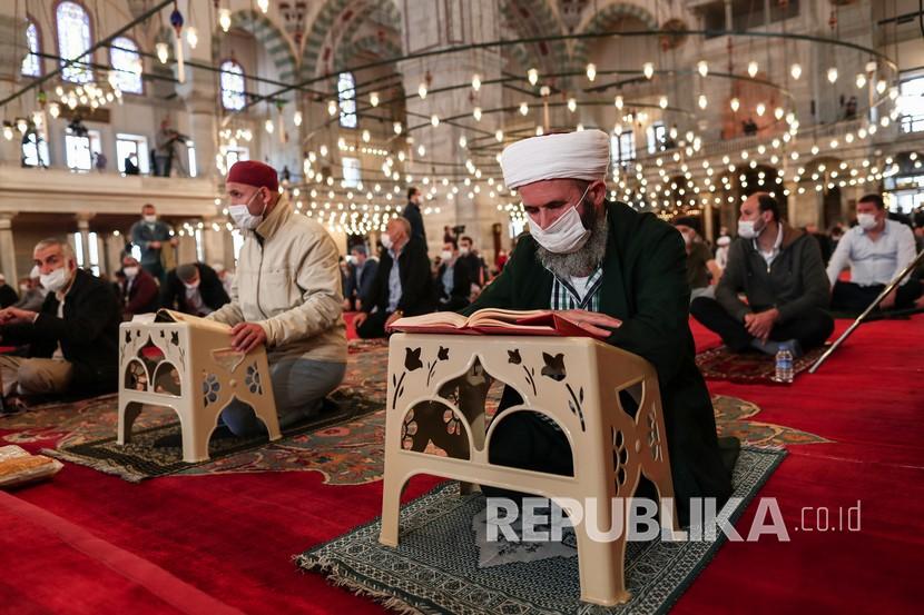 Jamaah membaca Quran saat mereka sholat Jumat di Masjid Fatih, Istanbul, Turki, Jumat (29/5). Shalat Jumat setelah 74 hari dengan jarak sosial di tengah pandemi virus corona. 