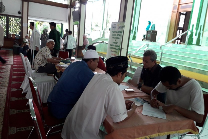 Jamaah menyerahkan zakat kepada petugas zakat Masjid Agung Sunda Kelapa.