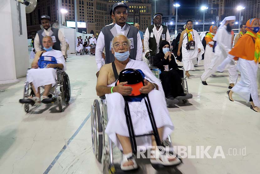 Jamaah tengah melakukan tawaf mengelilingi Ka'bah dengan bantuan petugas pendorong kursi roda.  (Ilustrasi)