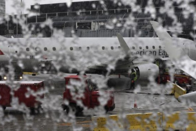 Jendela pesawat American Eagle tertutupi es. Ratusan penerbangan dibatalkan di Chicago menyusul cuaca buruk.