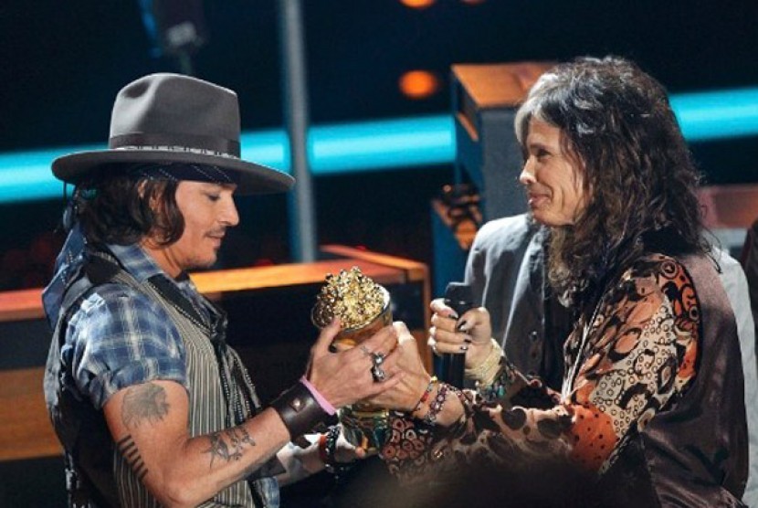 Johny Depp saat memberikan popcorn emas ke vokalis Aerosmith, Steve Tyler di ajang MTV Music Awards.