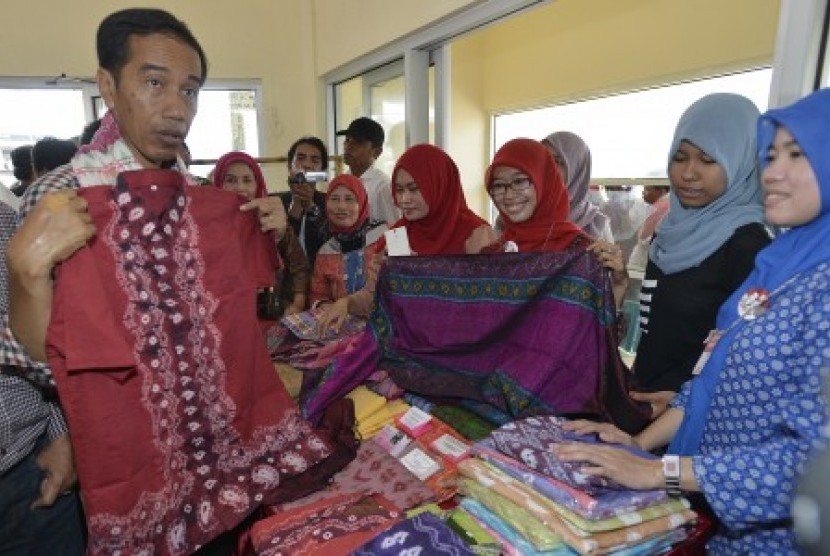  Joko Widodo (kiri) melihat hasil kerajinan kain songket ketika berkunjung ke sentra usaha mikro, kecil, dan menengah (UMKM) Tuan Kentang, di Kelurahan Tuan Kentang, Kecamatan Seberang Ulu Satu, Palembang, Sumatera Selatan, Rabu (25/6). 