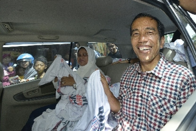  Jokowi dan istrinya, Iriana membagikan kaus ketika berkampanye mengunjungi kawasan Pasar Kota, Gresik, Jawa Timur, Ahad (29/6).