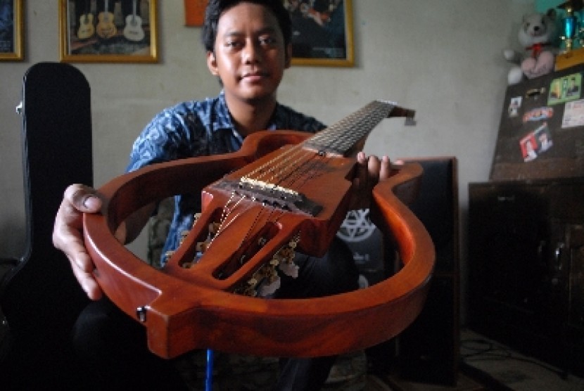JOMBANG -- GITAR NILON 12 DAWAI. Bayu Angga Pridahastama (24) mahasiswa Universitas Negeri Surabaya, jurusan Sendratasik, Seni Musik, mayor gitar klasik semester 8 menunjukan gitar klasik elektrik dua belas dawai hasil karya skripsinya yang mempunyai dua k