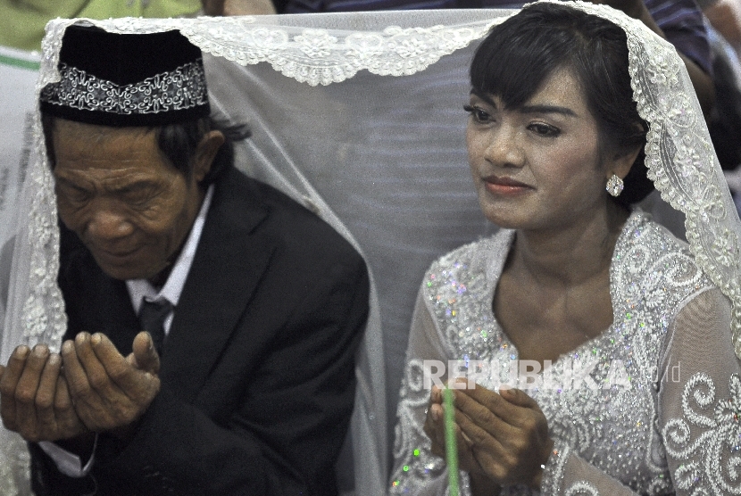 Joni (55) dan Isa (30) berdoa bersama seusai ijab kabul pernikahan disaksikan Direktur Rehabilitas Sosial Anak Nahar (kiri) di Gedung Kelurahan Pekojan Tambora, Jakarta Barat, Jumat (7/7).