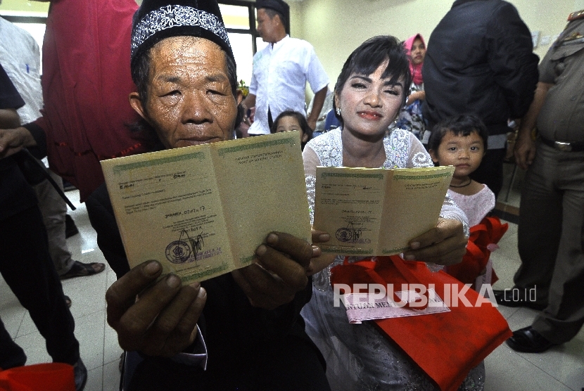 Joni (55) dan Isa (30) memperlihatkan buku nikahnya seusai ijab kabul di Gedung Kelurahan Pekojan Tambora, Jakarta Barat, Jumat (7/7). 