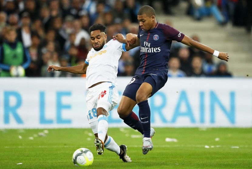 Jordan Amavi (kiri) dari Olympique Marseille mencoba menghalangi pemain Paris Saint-Germain Kylian Mbappe (kanan) pada pertandingan Ligue 1 antara kedua tim di Stadion Velodrome, Marseille, Prancis, Ahad (22/10).