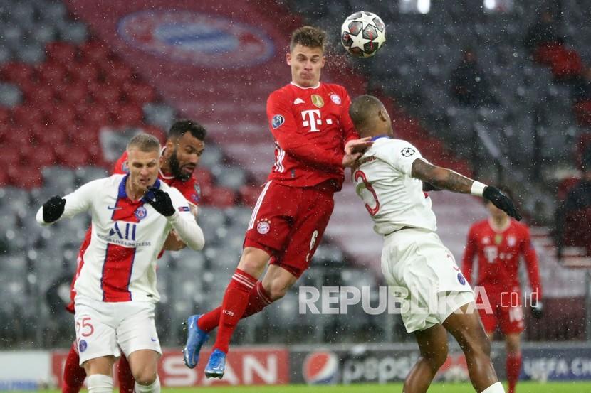 Joshua Kimmich dari Bayern, kiri, dan Presnel Kimpembe dari PSG melompat untuk merebut bola pada pertandingan sepak bola perempat final Liga Champions antara Bayern Munchen dan Paris Saint Germain di Munchen, Jerman, Kamis (8/4) dini hari WIB. 